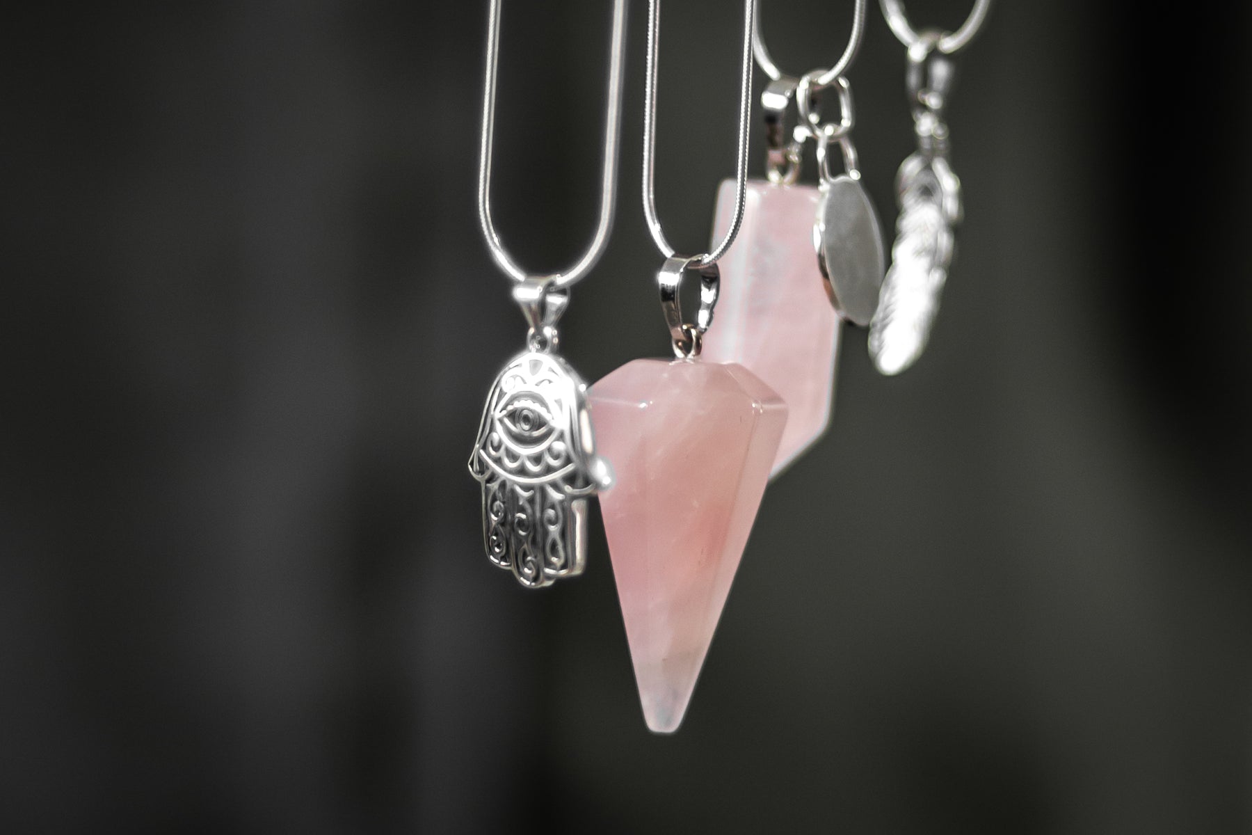 An array of of rose quartz crystals and sterling silver charms dangling in unison. 