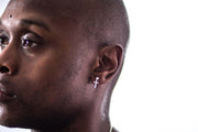Displayed on a male model in ear a Men's single sterling silver ball stud earring with a dangle cross.