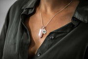 Full view of rose quartz pink bullet and silver charm necklace on lady's neckline.