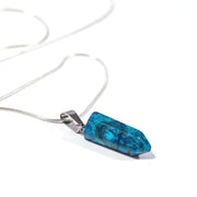 Side view of Blue Agate crystal with swirls of black throughout pendant. 
