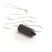 Side view of black Obsidian bullet point necklace with silver tone snake chain.