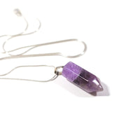Close up side view of natural crystal amethyst bullet pendant with stainless steel snake chain.