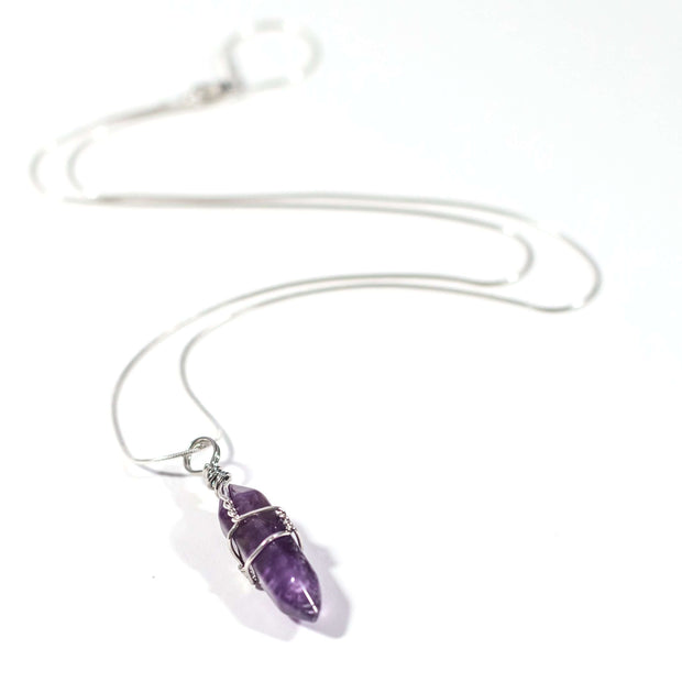 Long range shot of Relaxation Amethyst necklace . Wrapped bullet pendant with stainless steel snake chain.